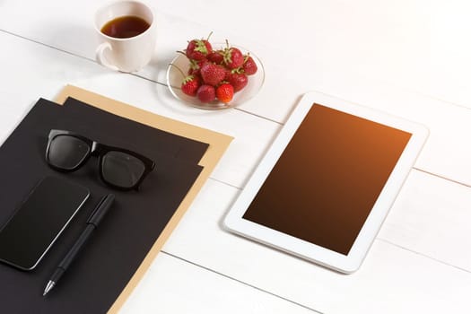 Modern workplace with digital tablet computer and mobile phone, cup of coffee, pen and empty sheet of paper. Top view and copy space for text