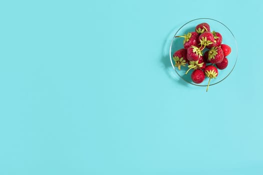 Ripe strawberries on the saucer isolated on mint background. Top view. Copy space. Still life mockup flat lay