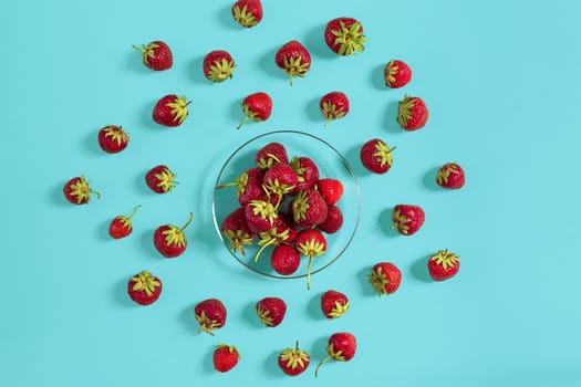 Ripe strawberries on the saucer isolated on mint background. Top view. Copy space. Still life mockup flat lay