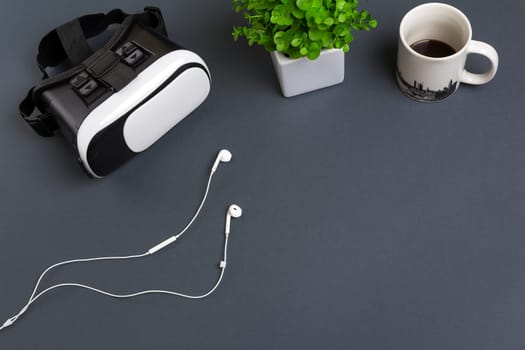 Virtual reality glasses and headphones on a gray background. Top view. Copy space