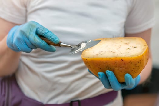 A man gives a cheese tasting to his customer. Cheese tasting. Cheese is cut with a special cheese knife. High quality photo