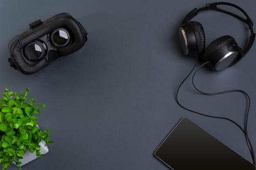 Virtual reality glasses and tablet with headphones on a gray background. Top view. Copy space