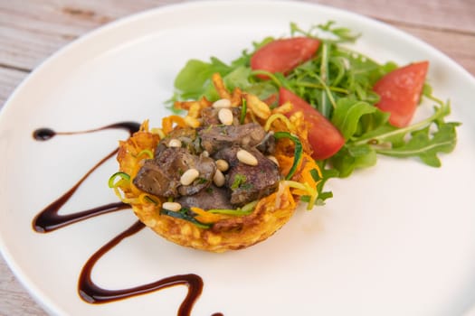 Recipe for poultry giblets in a nest of fried potatoes with rocket and tomato salad. High quality photo