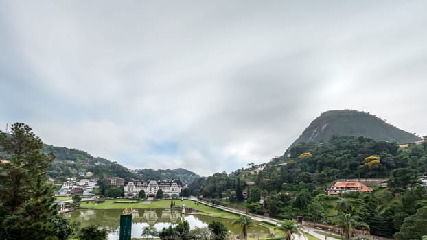 Enjoy the stunning view of Quitandinha Palace surrounded by hills and mountains with a green landscape and cloudy sky during sunrise.