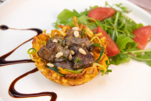 Recipe for poultry giblets in a nest of fried potatoes with rocket and tomato salad. High quality photo