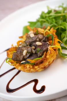 Recipe for poultry giblets in a nest of fried potatoes with rocket and tomato salad. High quality photo