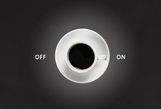 Coffee in white cup with a lettering on and off on black slate background, top view