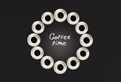 Cups with coffee, stacked in a circle. Clock consist of twenty cups. Alarm clock. Black background. Concept time to coffee