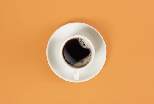 Arrows of a clock in a cup of coffee on orange background. View from above. Still life. Mock up. Flat lay. Copy space