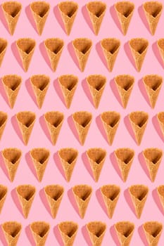 Sugar waffle cone for ice cream arranged in pattern on pink background. The image with copy space can be used as a background for the design of the confectionery menu, cards, greetings, invitations, pattern