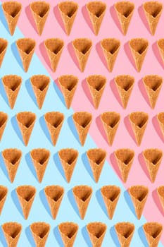 Sugar waffle cone for ice cream arranged in pattern on pink and mint background. The image with copy space can be used as a background for the design of the confectionery menu, cards, greetings, invitations, pattern