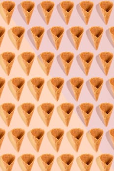 Sugar waffle cone for ice cream arranged in pattern on pink background. The image with copy space can be used as a background for the design of the confectionery menu, cards, greetings, invitations, pattern