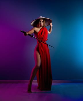 the sexy girl in a red cape and an Asian hat with a katana in her hand in neon lights on a copy paste background