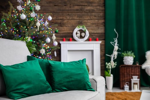 Bottle-colored pillows in the foreground and Christmas decoration in the background. Christmas tree and fireplace in a soft blur.
