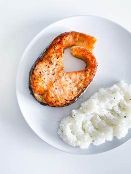 Glazed salmon fillet with rice garnish close-up on a plate. horizontal view from above