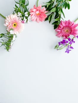 japanese dianthus, gerbera, matthiola and laurel leaves. floral frame with empty space for text or inscription. spring postcard