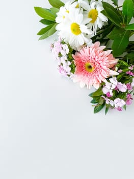 japanese dianthus, gerbera, chamomile and laurel leaves. floral frame with empty space for text or inscription. spring postcard