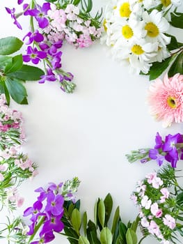 japanese dianthus, gerbera, chamomile, matthiola and laurel leaves. floral frame with empty space for text or inscription. spring postcard