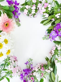 japanese dianthus, gerbera, chamomile, matthiola and laurel leaves. floral frame with empty space for text or inscription. spring postcard