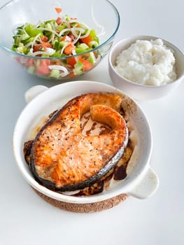 Healthy balanced meal lunch plate - baked salmon with rice and vegetables on a light background, top view