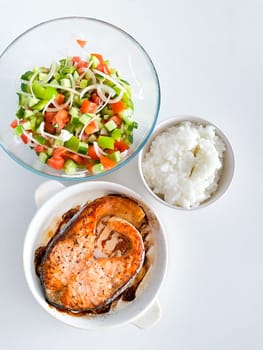 Healthy balanced meal lunch plate - baked salmon with rice and vegetables on a light background, top view