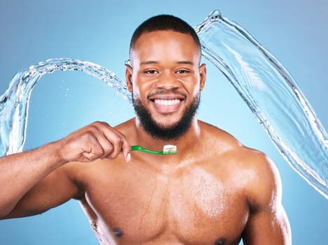 Black man, face and toothbrush with splash of water, dental and brushing teeth for hygiene on blue background. Cleaning, wet and male in portrait with smile for oral care product and toothpaste.