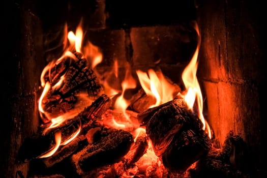 bright flame of fire burns in a fireplace in the old house in winter evening