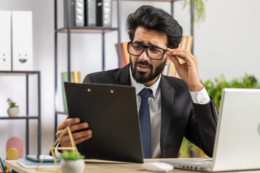 Tired indian businessman feeling worried about financial problem, stress at home office workplace. Indian freelancer broker man frustrated thinking of money debt, budget loss, bankruptcy. Overworking