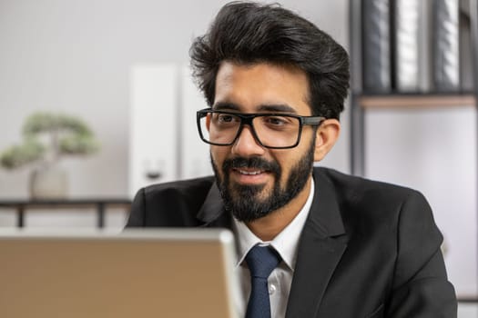 Close-up portrait indian bearded businessman face freelancer at home office workplace working on laptop computer. Manager freelancer indian man works on notebook send messages makes online purchases