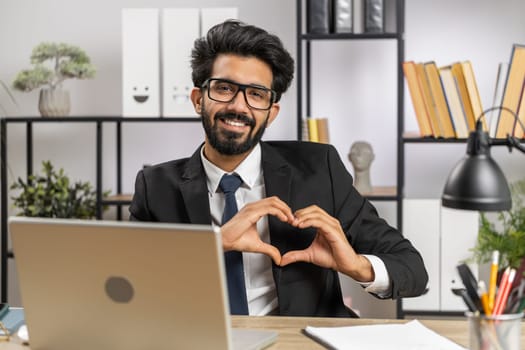 I love you. Indian business man makes symbol of love, showing heart sign to camera, express romantic feelings, express sincere positive feelings at home office workplace. Charity, gratitude, donation