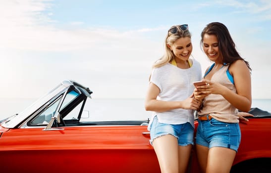 Travel more, worry less. two friends using a smartphone on a summers road trip