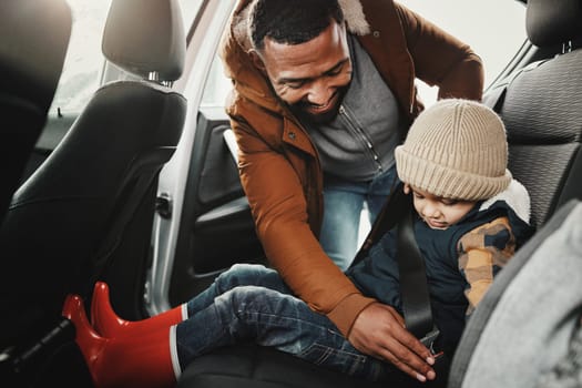 Father help child fasten seat belt leaving for vacation, trip or holiday in a car before travel together. Transport, transportation and dad or parent with kid in a vehicle for a getaway.