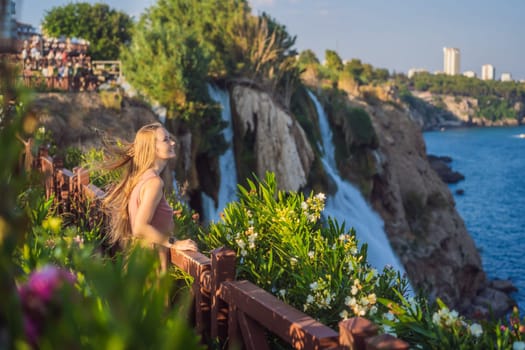 Beautiful woman with long hair on the background of Duden waterfall in Antalya. Famous places of Turkey. Lower Duden Falls drop off a rocky cliff falling from about 40 m into the Mediterranean Sea in amazing water clouds. Tourism and travel destination photo in Antalya, Turkey. Turkiye.