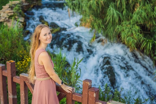 Beautiful woman with long hair on the background of Duden waterfall in Antalya. Famous places of Turkey. Lower Duden Falls drop off a rocky cliff falling from about 40 m into the Mediterranean Sea in amazing water clouds. Tourism and travel destination photo in Antalya, Turkey. Turkiye.