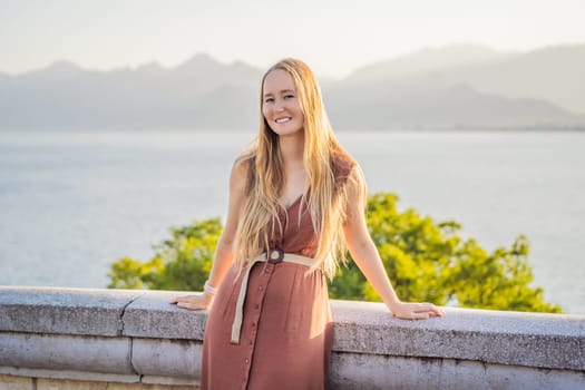 Happy woman tourist on background of Antalya sea and mountain views, sea in Turkey Antalya City. female tourist traveler discover interesting places and popular attractions and walks in the old city Kalechi of Antalya, Turkey. Turkiye.