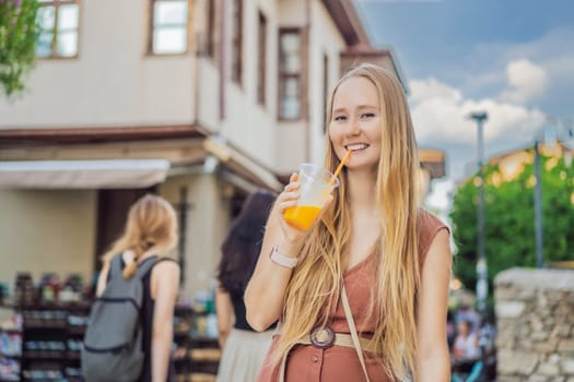 Happy woman tourist with fresh juice on background of old street of Antalya. female tourist traveler discover interesting places and popular attractions and walks in the old city Kalechi of Antalya, Turkey. Turkiye.