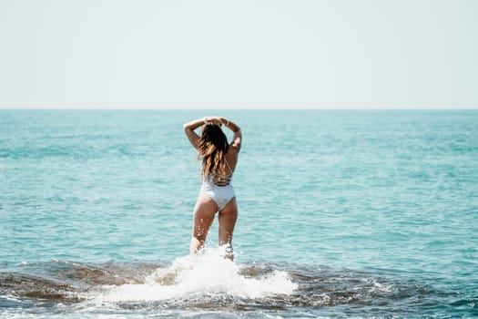 Woman sea yoga. Back view of free calm happy satisfied woman with long hair standing on top rock with yoga position against of sky by the sea. Healthy lifestyle outdoors in nature, fitness concept.