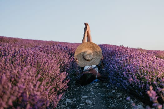 Selective focus. The girls legs stick out of the bushes, warm sunset light. Bushes of lavender purple in blossom, aromatic flowers at lavender fields.