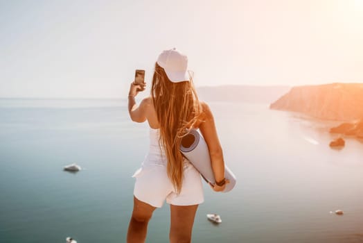 Young woman with black hair, fitness instructor in pink sports leggings and tops, doing pilates on yoga mat with magic pilates ring by the sea on the beach. Female fitness daily yoga concept