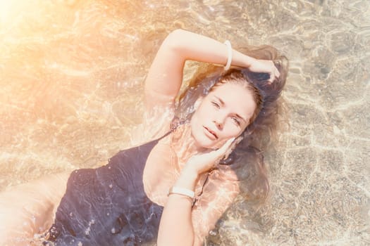 Woman travel sea. Young Happy woman in a long red dress posing on a beach near the sea on background of volcanic rocks, like in Iceland, sharing travel adventure journey