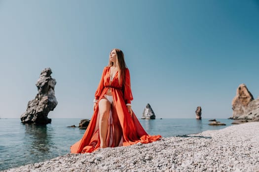 Woman travel sea. Happy tourist taking picture outdoors for memories. Woman traveler looks at the edge of the cliff on the sea bay of mountains, sharing travel adventure journey.