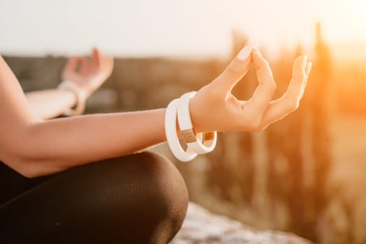 Well looking middle aged woman with long hair, fitness instructor in leggings and tops doing stretching and pilates on the rock near forest. Female fitness yoga routine concept. Healthy lifestyle.