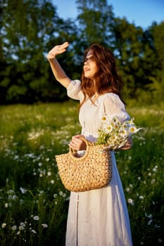 a woman in a white dress stands in nature covering herself with her hands from the bright sun. High quality photo