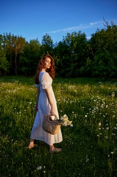 a beautiful, happy woman in a light dress stands in a chamomile field in the rays of the setting sun. High quality photo