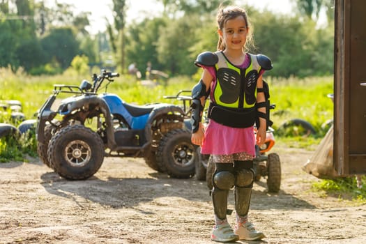 The little girl in protective clothing. Electric quad bike electric car for children popularizes green technology