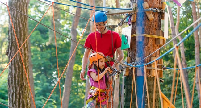 male instructor helps the child on the rope road in the training camp