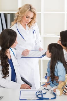 Young mother and girl in pediatrician office, doctor giving diagnosis and prescription