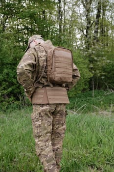Back View of Soldier with Full Gear and Tactical Backpack Standing in Forest