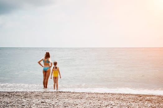 Happy loving family mother and daughter having fun together on the beach. Mum playing with her kid in holiday vacation next to the ocean - Family lifestyle and love concept.