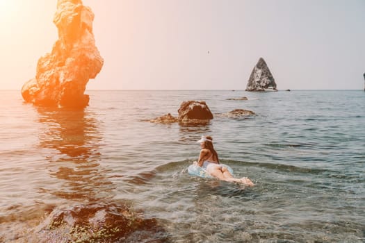 Woman summer sea. Happy woman swimming with inflatable donut on the beach in summer sunny day, surrounded by volcanic mountains. Summer vacation concept